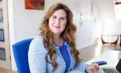 Woman with long chestnut hair in blue sitting at desk